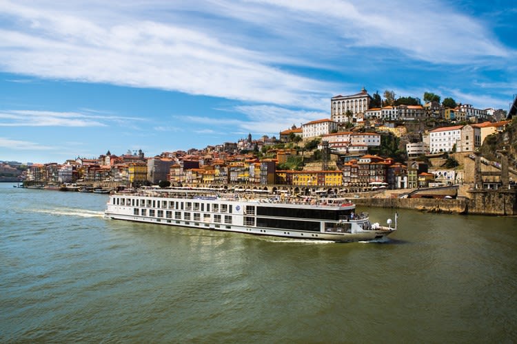 Scenic river cruise ship sailing through a picturesque European landscape.